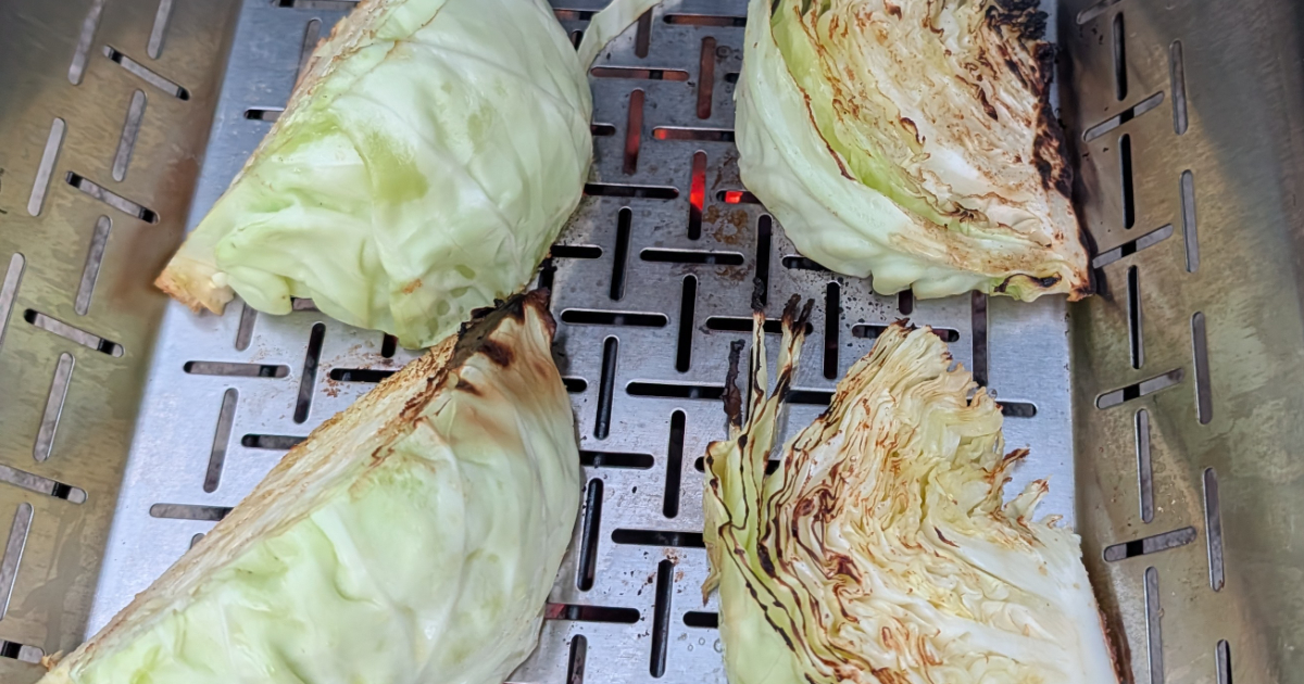 Cabbage quarters being grilled in a vegetable basket on a barbecue
