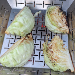 Cabbage quarters being grilled in a vegetable basket on a barbecue