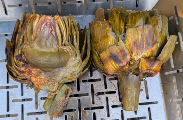 Artichokes in a veggie basket grilling on the barbecue