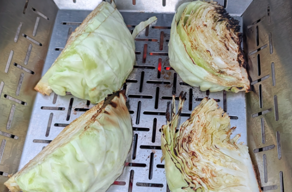 Quartered cabbages grilling in a veggie basket on the barbecue